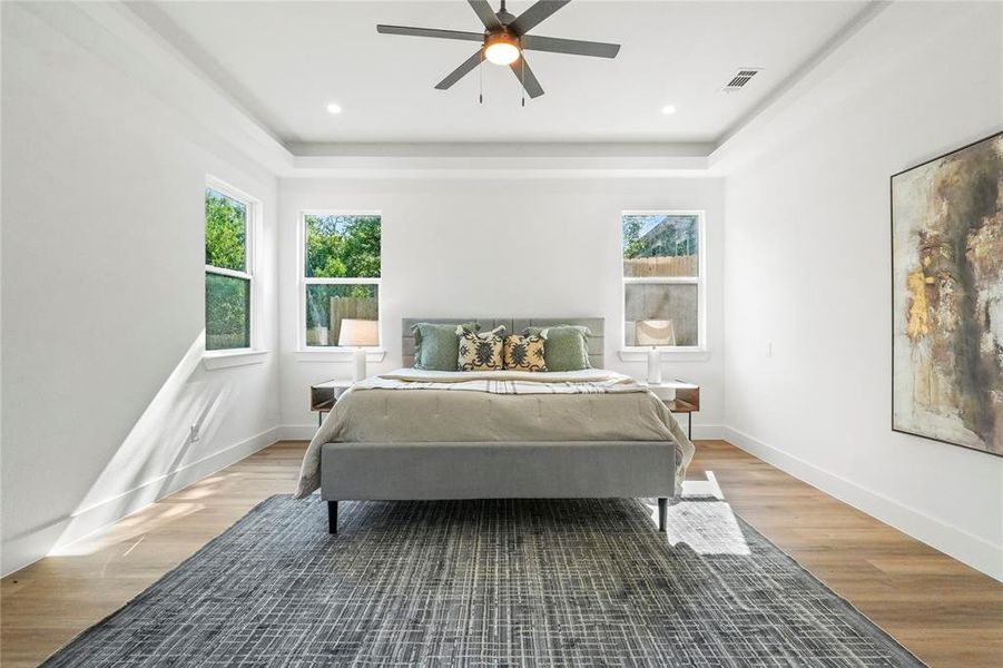 Bedroom featuring wood finished floors, ceiling fan, a raised ceiling, and recessed lighting