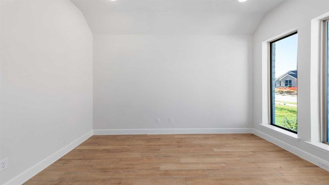 Unfurnished room with plenty of natural light, vaulted ceiling, and light wood-type flooring