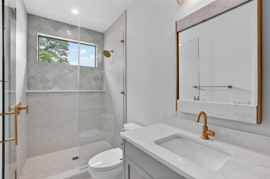 A well-lit contemporary bathroom boasts a spacious walk-in shower and elegant vanity with modern fixtures.