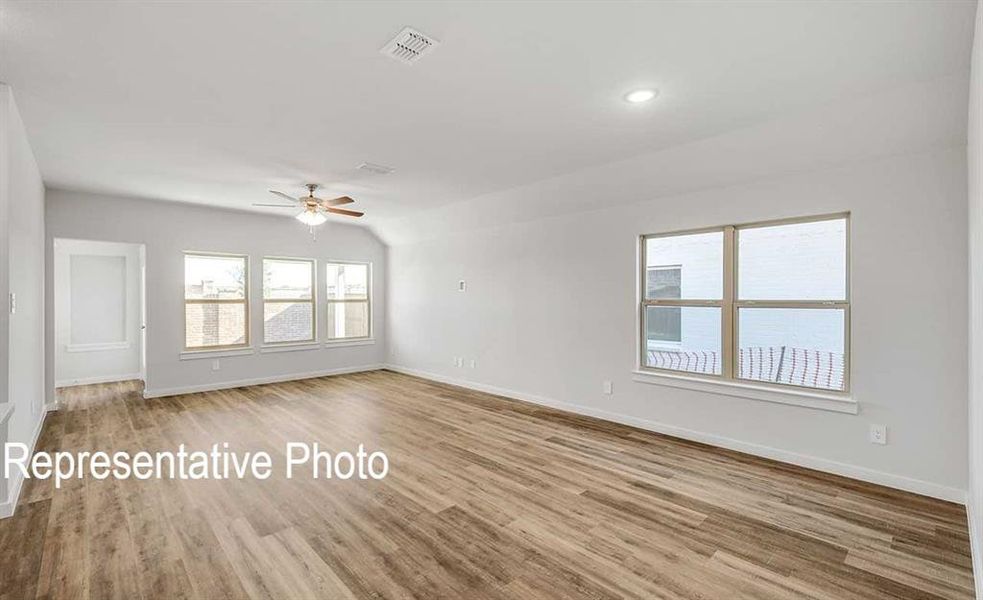 Empty room featuring ceiling fan, light wood-type flooring, and lofted ceiling