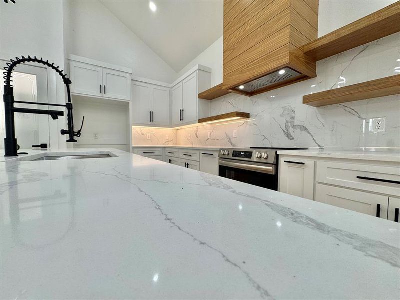 Kitchen featuring open shelves, white cabinetry, light stone countertops, electric stove, and high vaulted ceiling Kitchen featuring open shelves, white cabinetry, light stone countertops, electric stove, and high vaulted ceiling