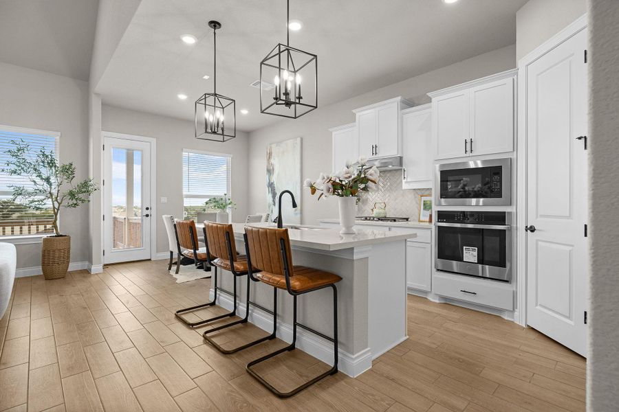 Kitchen with a breakfast bar, backsplash, a center island with sink, hanging light fixtures, and oven