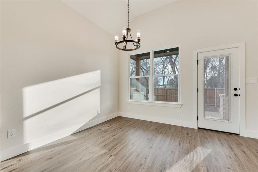 Unfurnished dining area with vaulted ceiling, a chandelier, and light wood-style floors