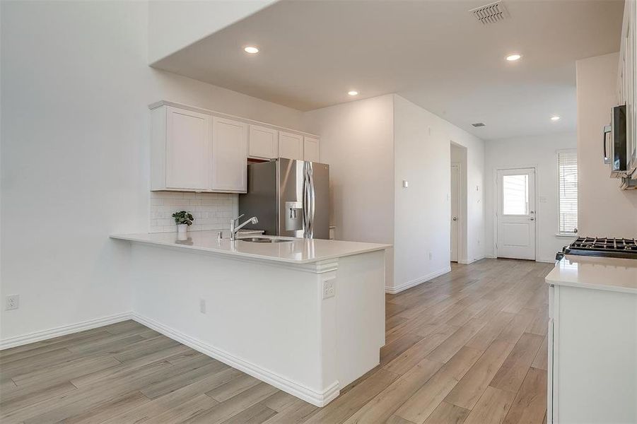 Kitchen with kitchen peninsula, stainless steel appliances, white cabinetry, and sink