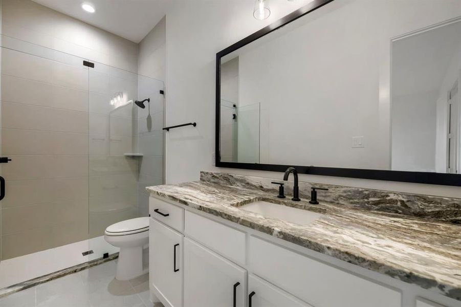 The bathroom features a spacious vanity with a stone countertop and a large mirror