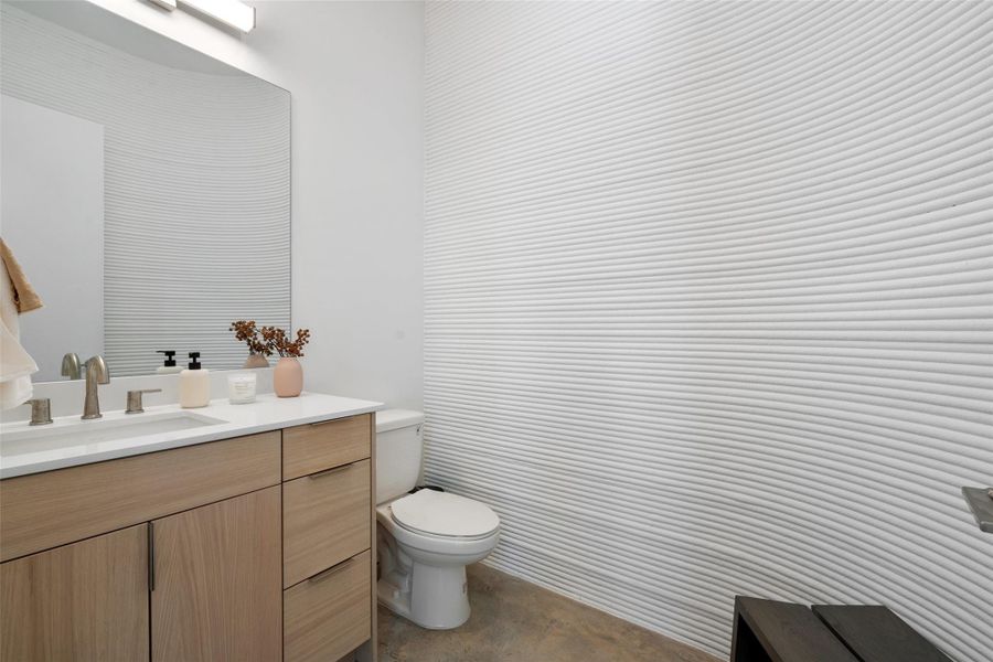 Bathroom featuring toilet, concrete floors, and vanity