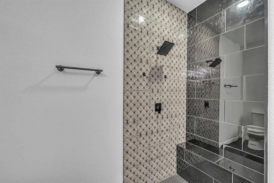 Bathroom featuring tiled shower and toilet