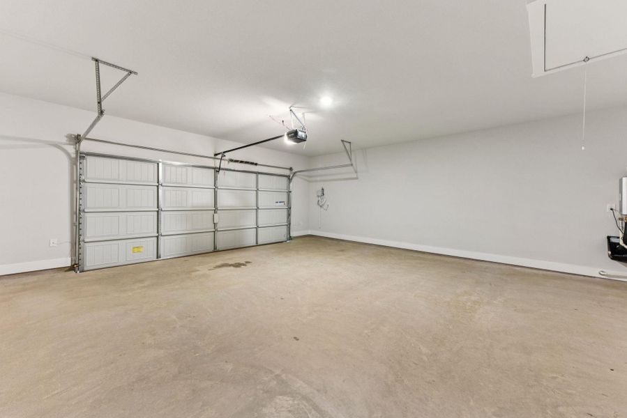 Garage with baseboards and a garage door opener Garage with baseboards and a garage door opener