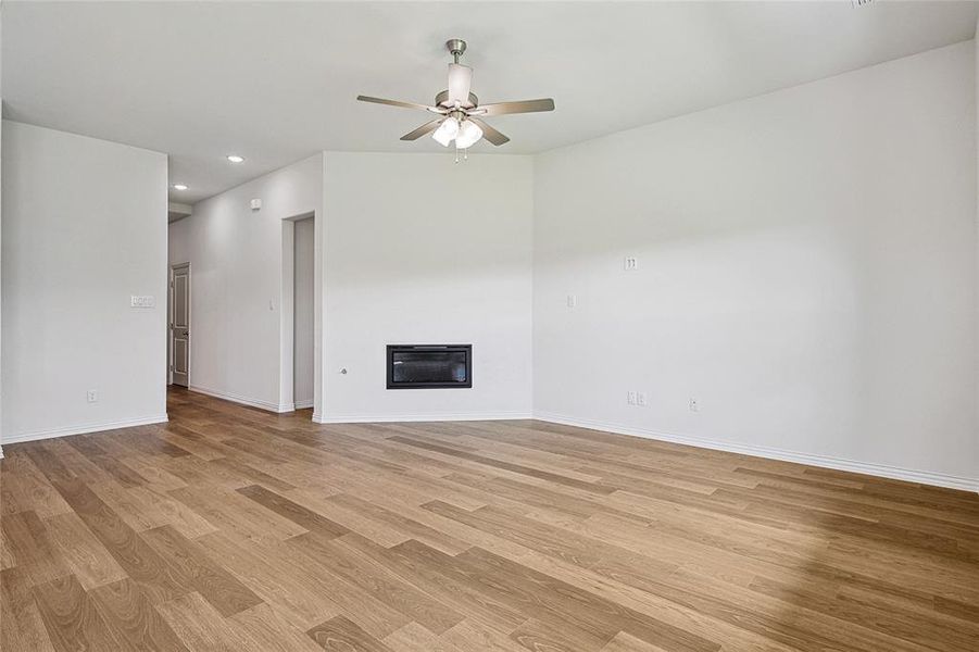 Unfurnished living room featuring ceiling fan and light wood-type flooring