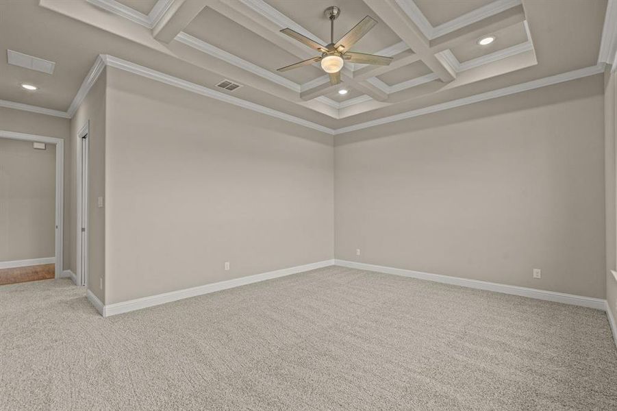 Spare room featuring light carpet, ceiling fan, coffered ceiling, ornamental molding, and beamed ceiling