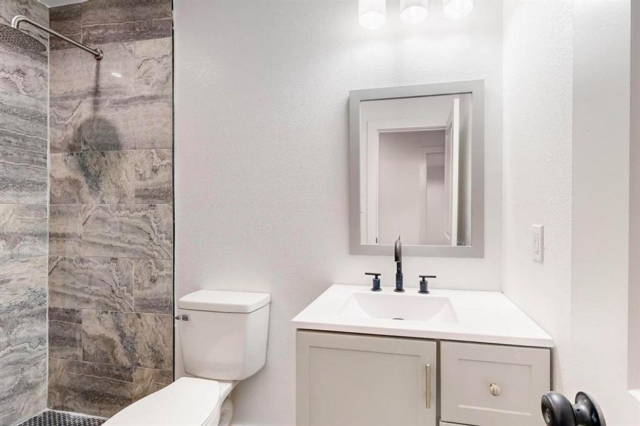 Bathroom featuring vanity, toilet, and a tile shower