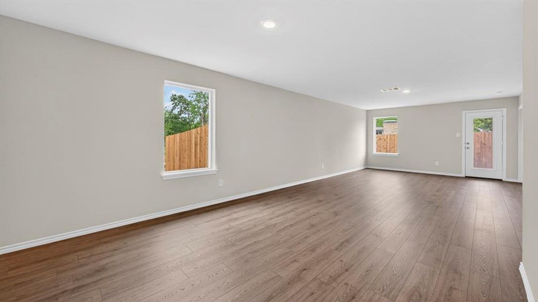 Spacious interior room with wood-finish flooring, light gray wall paint, and recessed ceiling lighting