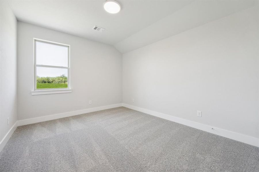 Spare room featuring light colored carpet and lofted ceiling