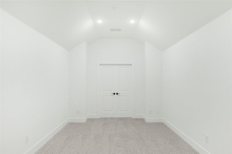 Empty bedroom with vaulted ceiling, gray carpet, and white double doors with black hardware Empty bedroom with vaulted ceiling, gray carpet, and white double doors with black hardware
