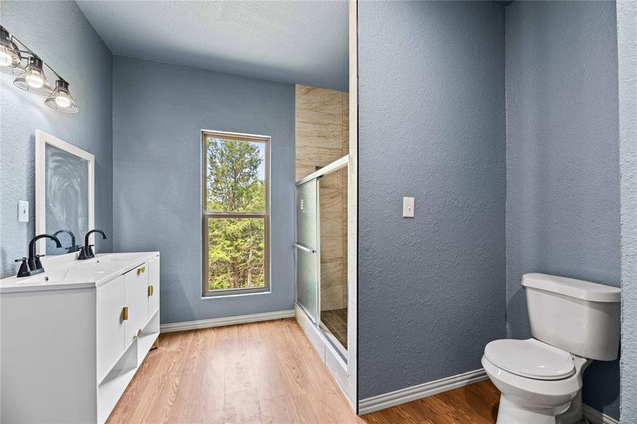 Bathroom featuring toilet, plenty of natural light, vanity, and hardwood / wood-style flooring Bathroom featuring toilet, plenty of natural light, vanity, and hardwood / wood-style flooring