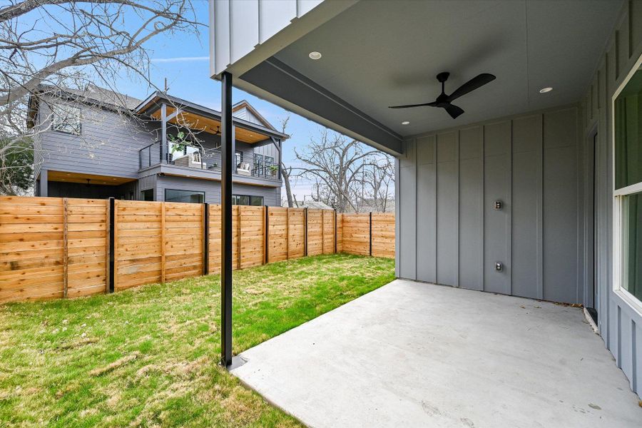 The private, fenced-in backyard offers a perfect patch of green for pets or urban gardening, all framed by modern vertical siding and clean architectural lines.