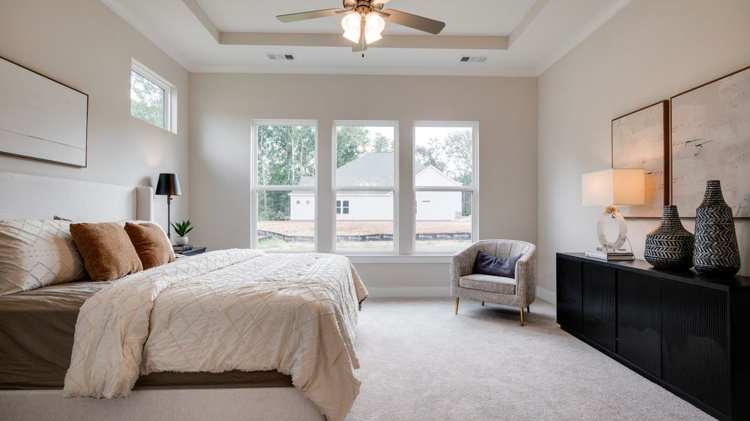 Primary bedroom with trey ceilings and sizeable windows connected to bathroom and walk-in closet