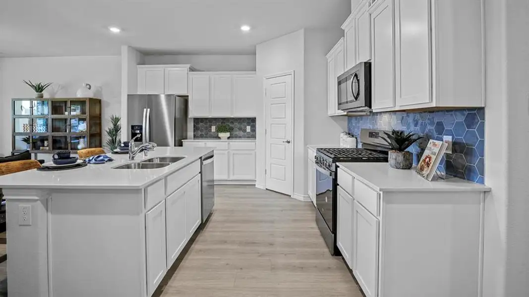 Kitchen featuring stainless steel appliances, tasteful backsplash, white cabinetry, a center island with sink, and recessed lighting