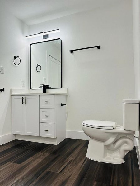 Half bathroom featuring vanity and dark wood-style flooring Half bathroom featuring vanity and dark wood-style flooring