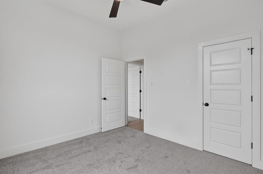 Interior room featuring light gray carpet flooring, white walls, and white five-panel doors Interior room featuring light gray carpet flooring, white walls, and white five-panel doors