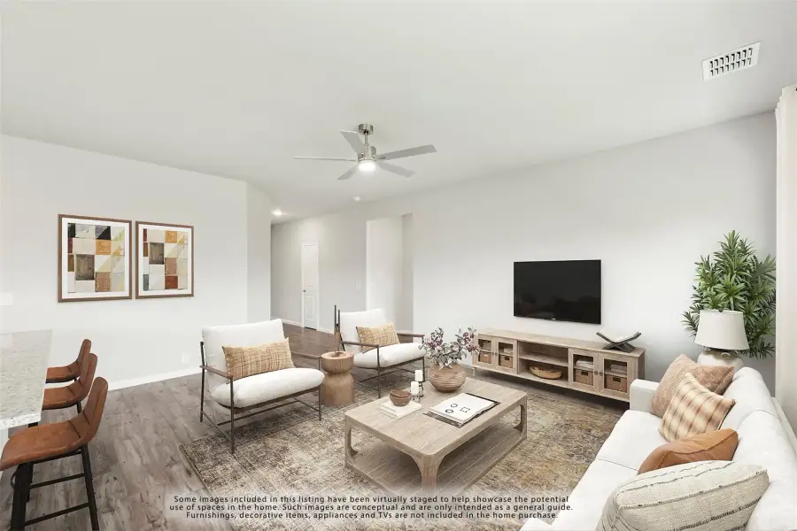 Living room with hardwood floors, ceiling fan, wall-mounted TV, and neutral furniture seating area