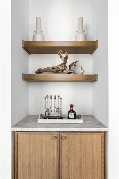 Custom built-in nook featuring wood-finish cabinetry, a light-toned countertop, and two floating shelves