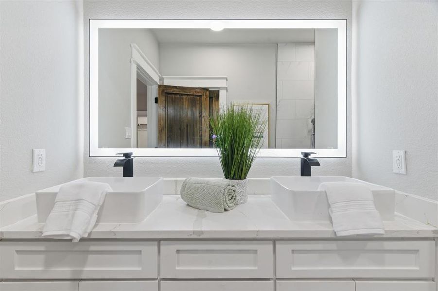 Bathroom with a textured wall and double vanity
