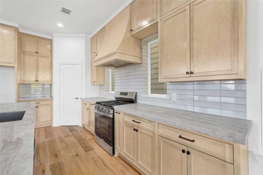 The kitchen features custom-built cabinets, Taj Mahal countertops, ample storage, and a walk-in pantry.