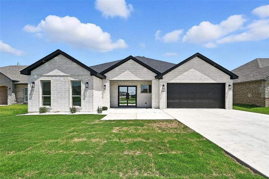 View of front of property with concrete driveway, an attached garage, a front yard, and brick siding