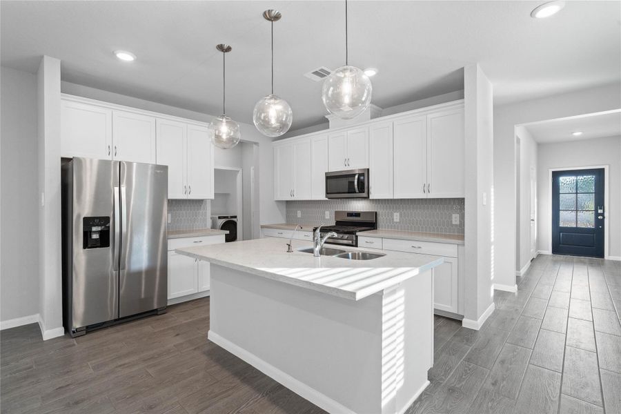 The extended quartz countertop creates a convenient breakfast bar, providing a casual and inviting space where stools can be added for quick meals or long conversations.