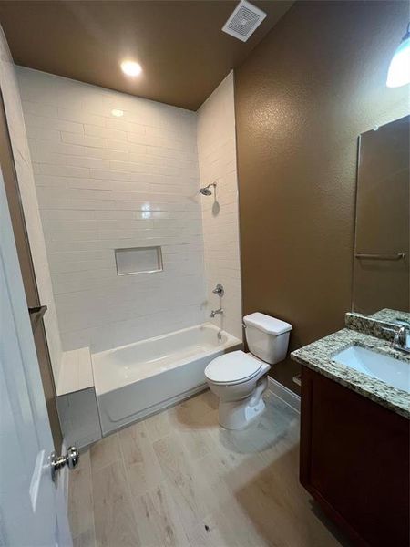 Bathroom with bathing tub / shower combination, vanity, light wood-style flooring, a textured wall, and recessed lighting Bathroom with bathing tub / shower combination, vanity, light wood-style flooring, a textured wall, and recessed lighting