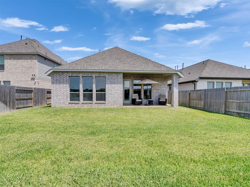 Charming brick home with a spacious, well-maintained backyard perfect for outdoor activities, featuring a cozy covered back porch for relaxation and entertaining.