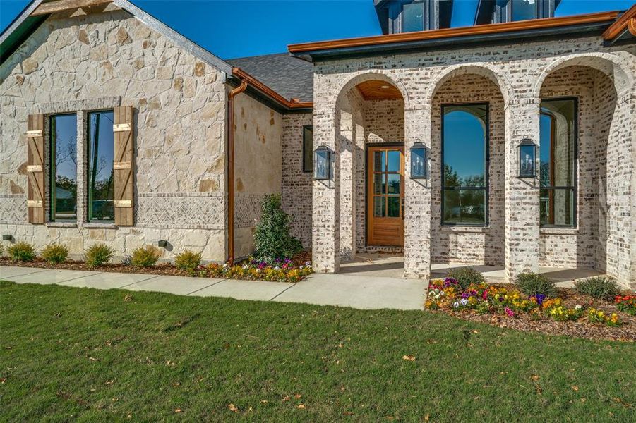 Doorway to property with a yard, brick siding, and stone siding Doorway to property with a yard, brick siding, and stone siding