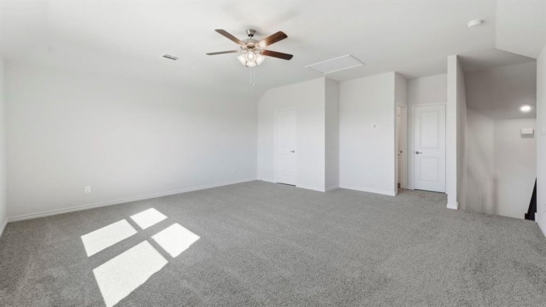Unfurnished bedroom with attic access, carpet floors, and a ceiling fan Unfurnished bedroom with attic access, carpet floors, and a ceiling fan