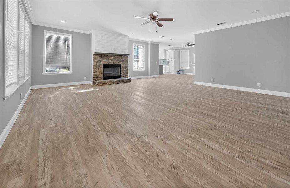 Unfurnished living room featuring crown molding, a fireplace, light wood finished floors, and recessed lighting