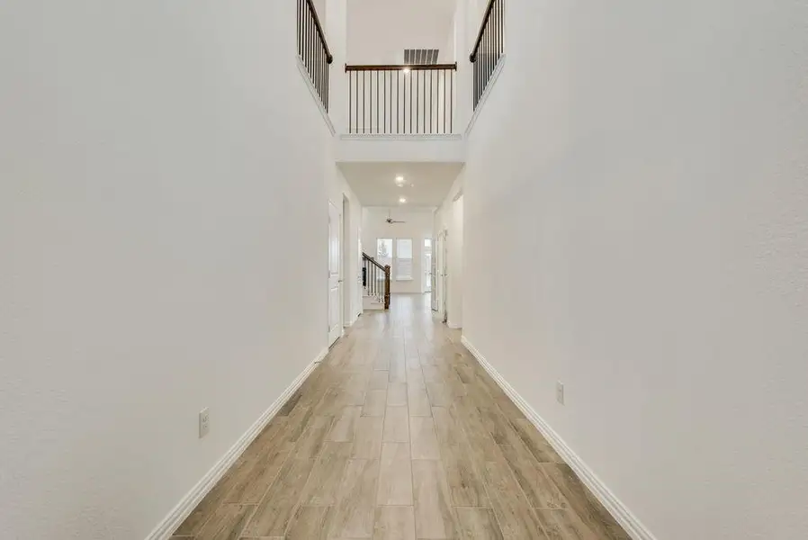 Hall featuring light hardwood / wood-style floors and a towering ceiling