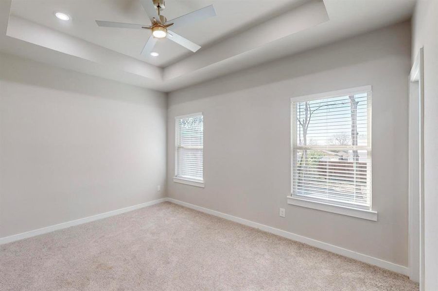 Carpeted spare room with ceiling fan and a raised ceiling