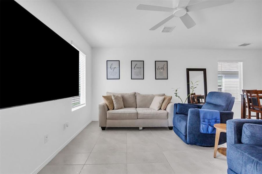 Living area featuring light tile patterned flooring and a ceiling fan