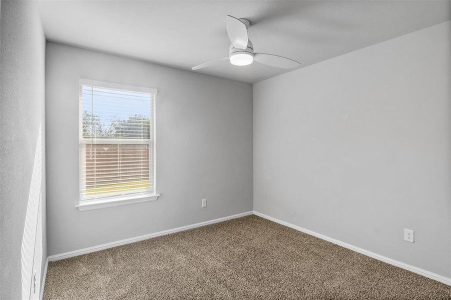 Carpeted spare room featuring plenty of natural light and ceiling fan