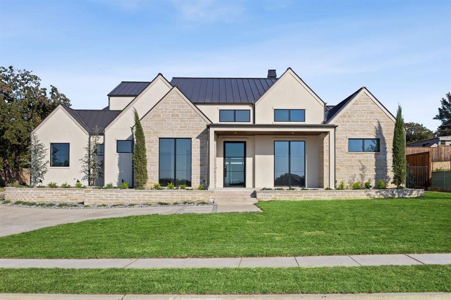 Modern inspired farmhouse with stone siding, a porch, a metal roof, and stucco siding Modern inspired farmhouse with stone siding, a porch, a metal roof, and stucco siding