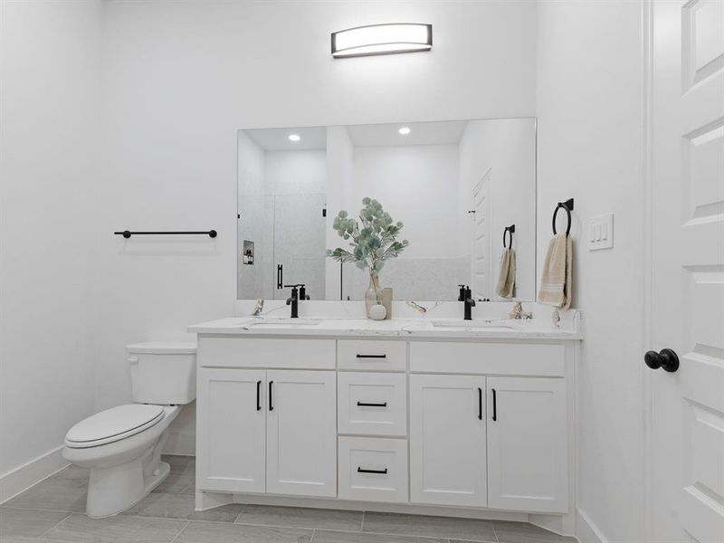 Full bath featuring double vanity, a sink, toilet, and a shower stall