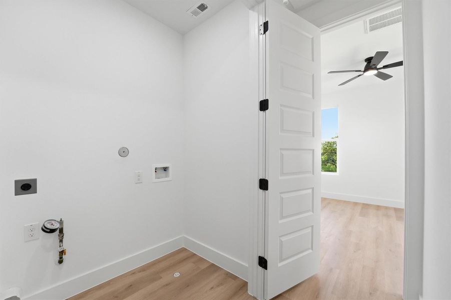 Dedicated laundry space featuring washer and dryer connections, wood-look flooring, and a clean, efficient layout conveniently located near bedroom areas for added ease and functionality.