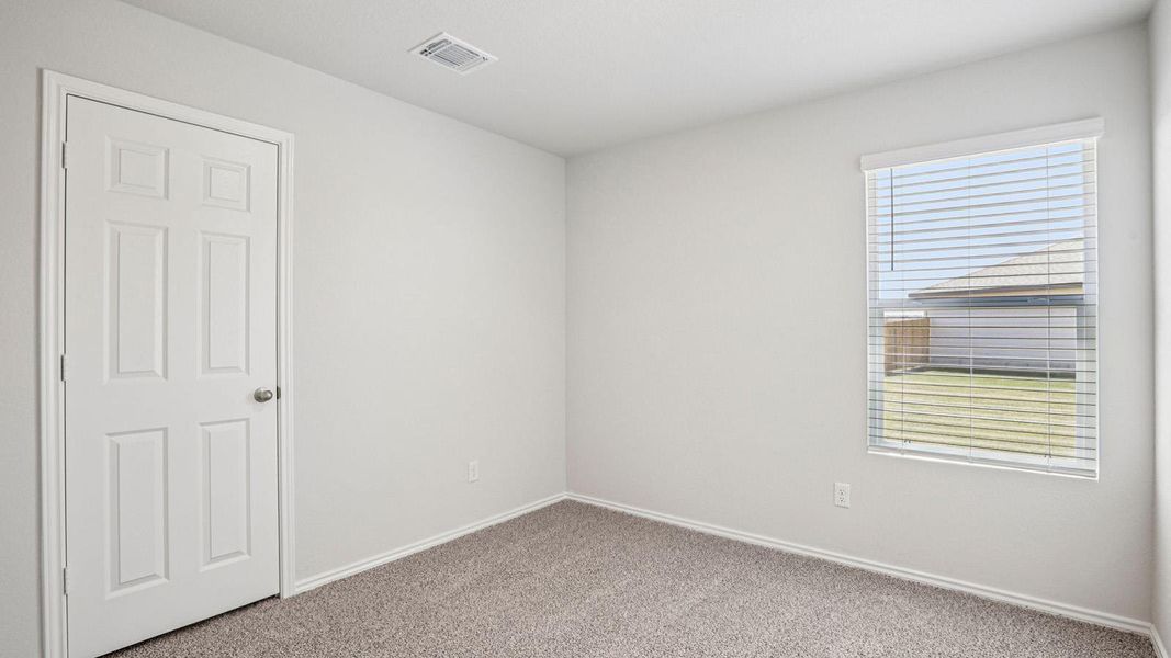 Carpeted room featuring a white paneled door with a silver knob, a window with horizontal blinds, and light-toned wall paint Carpeted room featuring a white paneled door with a silver knob, a window with horizontal blinds, and light-toned wall paint