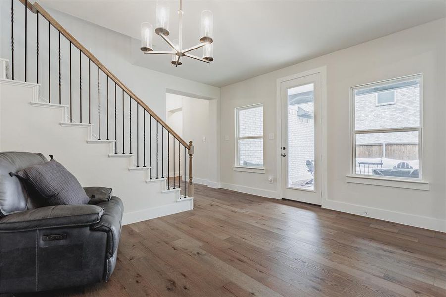Spacious interior featuring wood-finish flooring, a modern chandelier, and a staircase with wrought iron balusters and a wood handrail