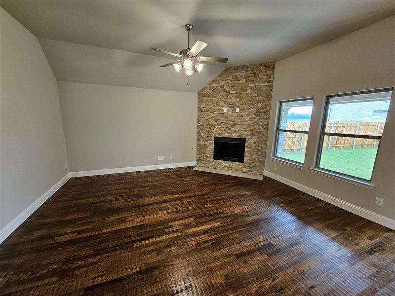 Family room with rich hardwood floors, a wall of windows, and ceiling fan. (Fireplace not included)