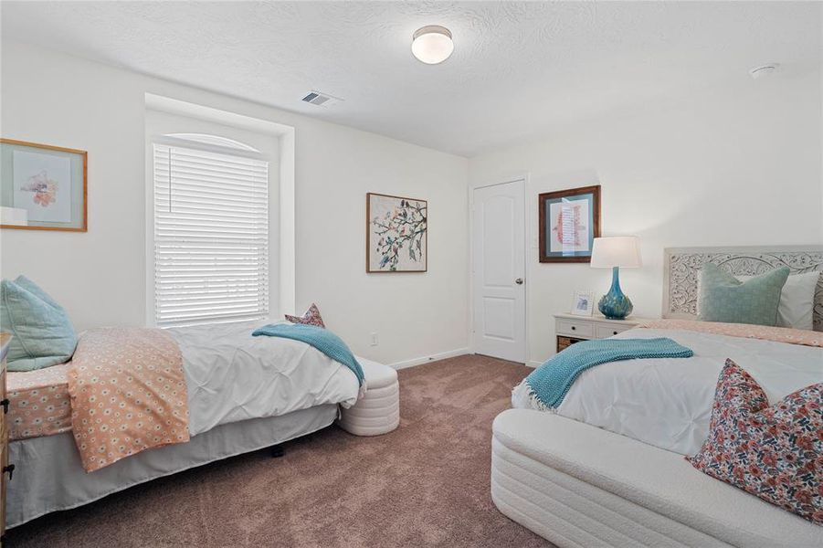 This secondary bedroom features high ceilings, lighting, custom paint, plush carpet, ample closet space, and a large window with privacy blinds!