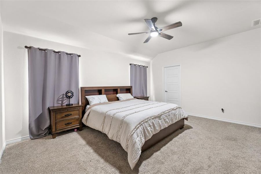 Bedroom with carpet flooring, lofted ceiling, and ceiling fan Bedroom with carpet flooring, lofted ceiling, and ceiling fan