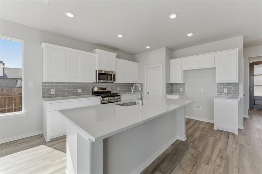 Kitchen with healthy amount of natural light, white cabinets, stainless steel appliances, tasteful backsplash, and recessed lighting