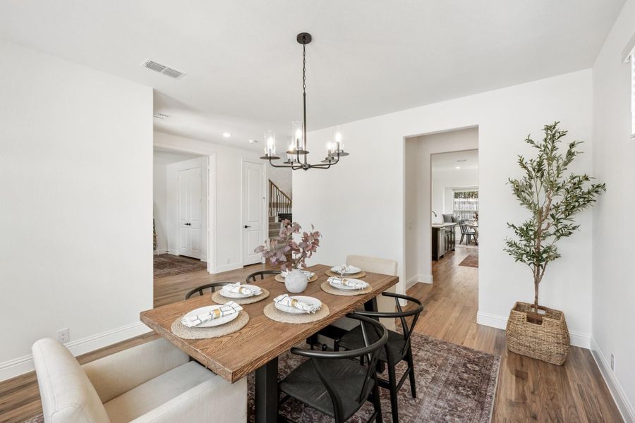 Dining room with wood table, black chairs, chandelier, and hardwood floors
