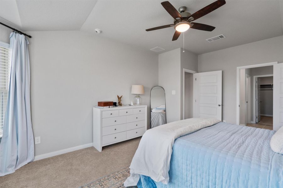 Carpeted room with a vaulted ceiling and a ceiling fan with integrated lighting Carpeted room with a vaulted ceiling and a ceiling fan with integrated lighting